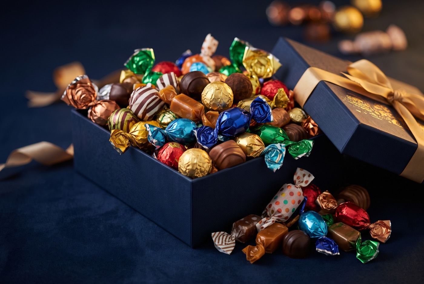 Open navy gift box overflowing with colorful wrapped candies